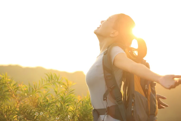 Cheering woman hiker open arms to the sunrise stand at mountain peak — Stock Photo, Image