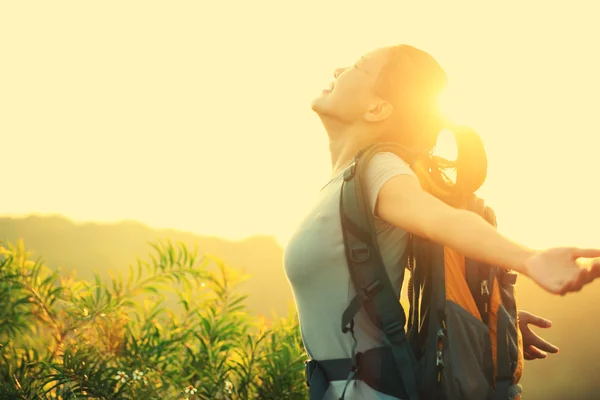 Cheering woman hiker open arms to the sunrise stand at mountain peak — Stock Photo, Image