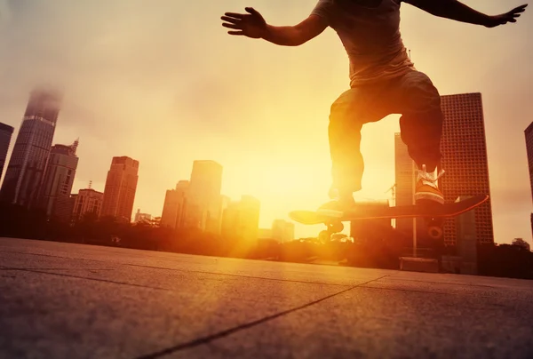 Skateboarder skateboarding při východu slunce města — Stock fotografie