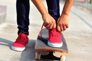 Ayakkabı bağı bağlayan genç bir kaykaycı.