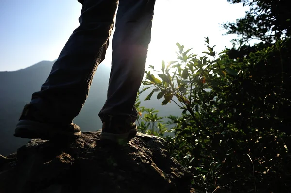 Mulher caminhante pernas ficar em montanha pico de rocha — Fotografia de Stock