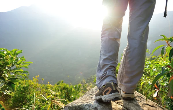Kvinnan hiker benen stå på mountain peak rock — Stockfoto