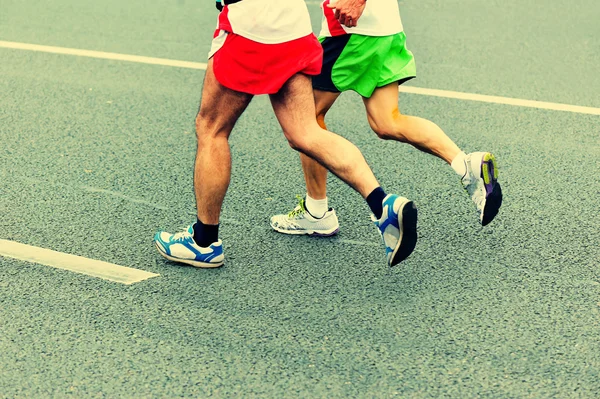 Unidentified marathon athletes legs running on city road — Stock Photo, Image