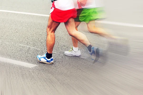 Невідомі спортсмени марафону біжать по міській дорозі — стокове фото