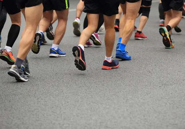 Maratón no identificado atletas piernas corriendo en la carretera de la ciudad —  Fotos de Stock