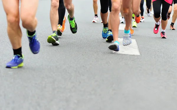 Unidentified marathon athletes legs running on city road — Stock Photo, Image