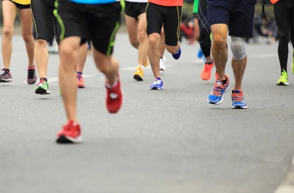 Unidentified marathon athletes legs running on city road — Stock Photo, Image