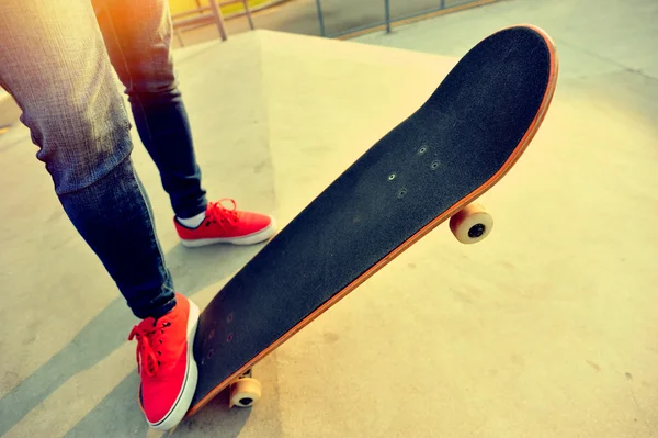 Jeune femme jambes skateboard au skatepark — Photo