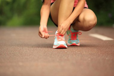 Bağcıklarını bağlayan genç bir kadın koşucu