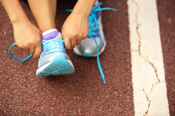 Young woman runner tying shoelaces — Stock Photo, Image