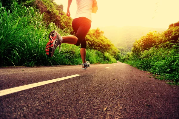 Genç fitness kadını orman yolunda koşuyor.