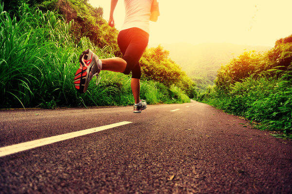 Young fitness woman running at forest trail