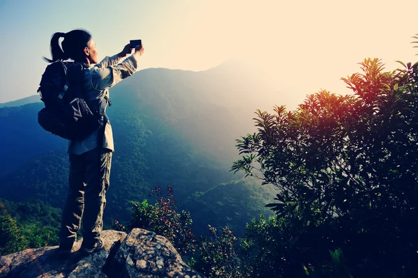 Turista na vrchol hory s smartphone — Stock fotografie