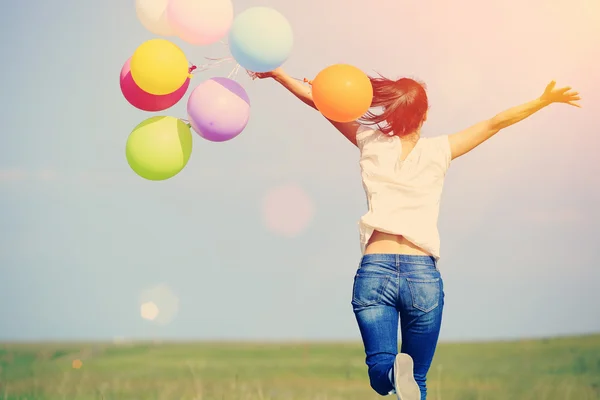 Woman running with colored balloons — Stock Photo, Image