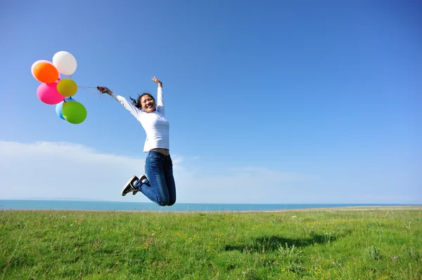 Frau springt mit Luftballons — Stockfoto