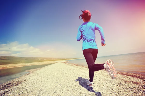 Woman running on stone beach — Stock Photo, Image