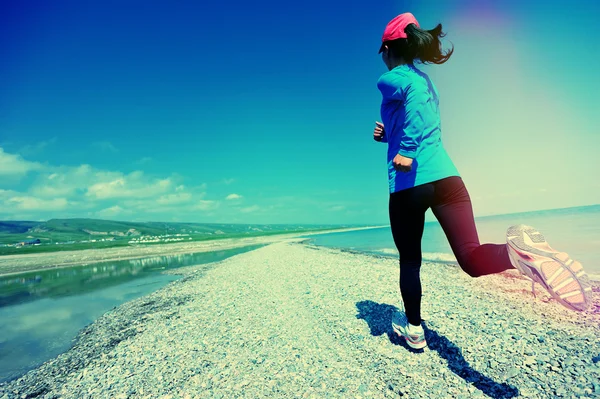 Женщина бежит по каменному пляжу — стоковое фото