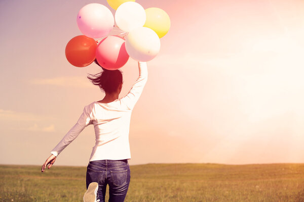 Woman running with colored balloons