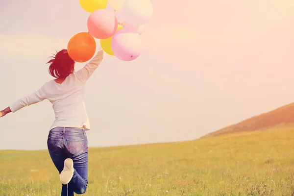 Woman running with colored balloons — Stock Photo, Image