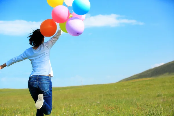 Woman running with colored balloons — Stock Photo, Image