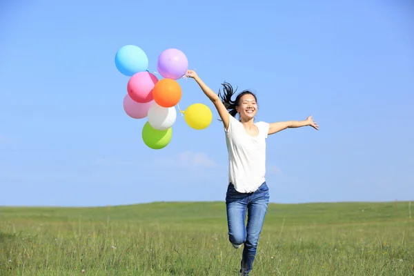 Woman running with colored balloons — Stock Photo, Image