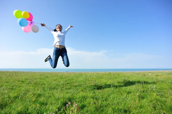 Frau springt mit Luftballons — Stockfoto