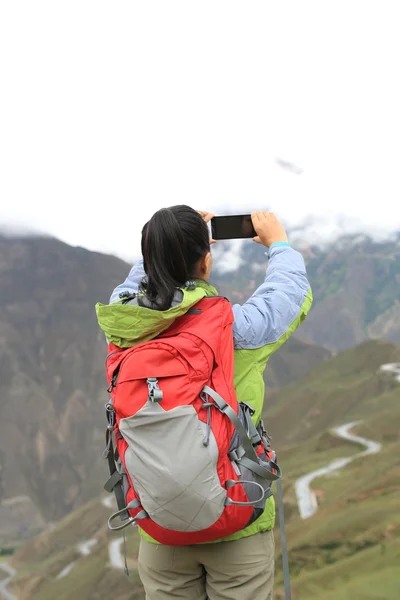 在山顶的智能手机上的徒步旅行者 — 图库照片