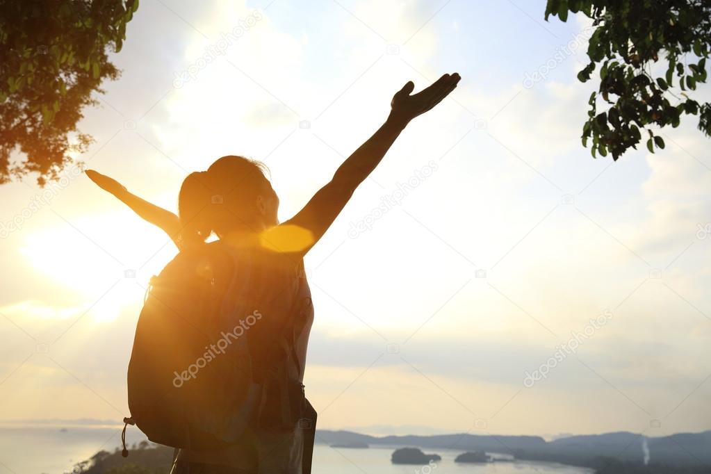 Woman with open arms at sunset