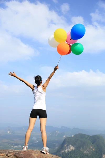 Asian woman on mountain with balloons — Stock Photo, Image