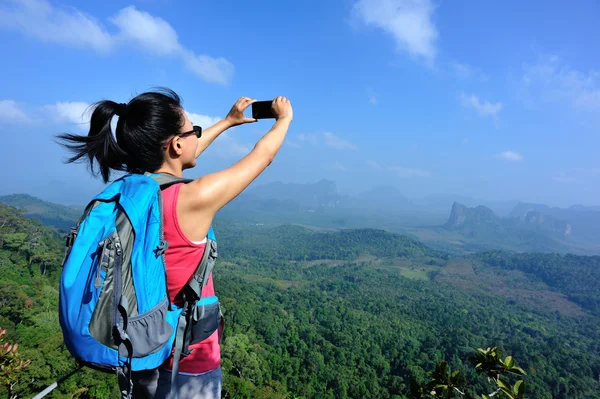 Turista na vrchol hory s smartphone — Stock fotografie