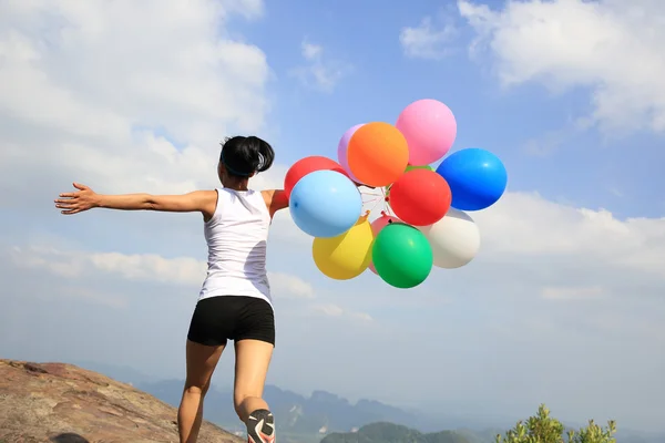 Asian woman on mountain with balloons — Stock Photo, Image