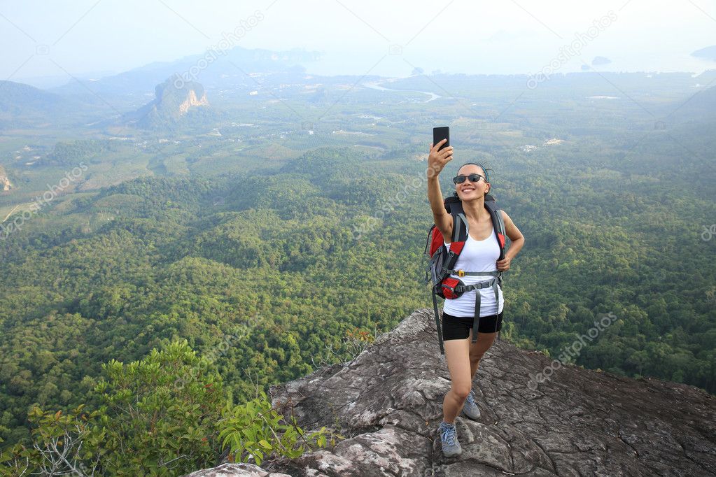 Hiker on mountain top with smartphone