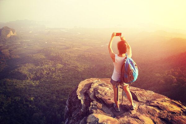 Hiker on mountain top with smartphone