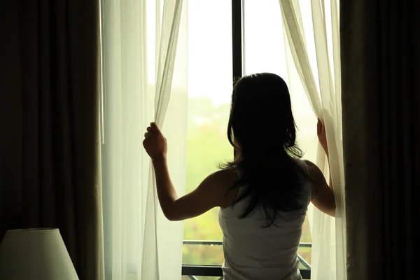 Mujer abriendo cortinas — Foto de Stock