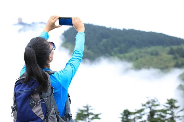 Turysta na szczycie góry z smartphone — Zdjęcie stockowe