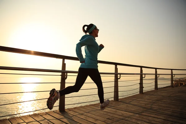 Deportiva mujer corriendo sobre la orilla del mar —  Fotos de Stock