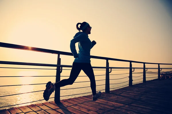 Deportiva mujer corriendo sobre la orilla del mar —  Fotos de Stock