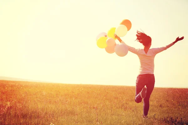 Asian woman running with balloons — Stock Photo, Image