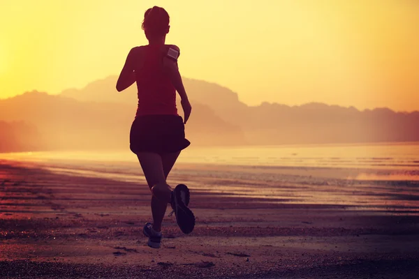 Silueta femenina corriendo en la playa —  Fotos de Stock