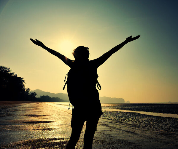 Cheering female silhouette at sunset beach