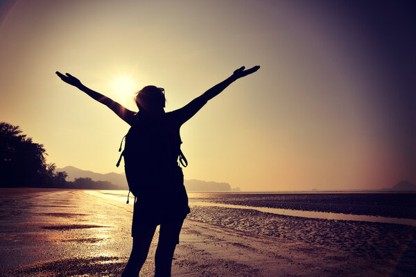 Cheering female silhouette at sunset beach