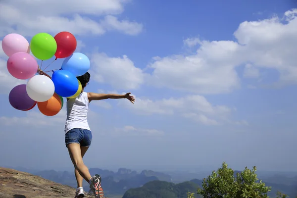 Young woman running with colorful balloons — Stock Photo, Image