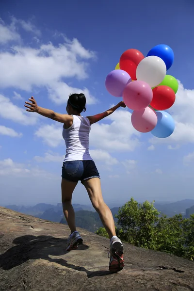 Junge Frau läuft mit bunten Luftballons — Stockfoto