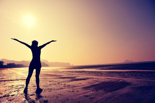 Cheering woman with open arms on beach