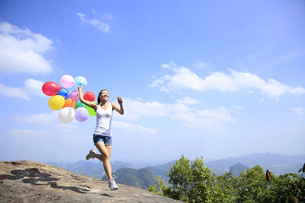 Asian woman running with colorful balloons — Stock Photo, Image