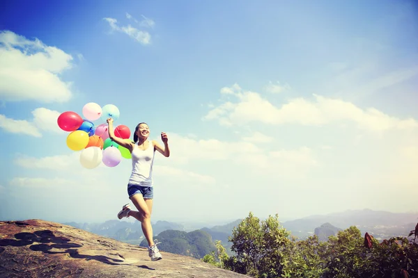 Asian woman running with colorful balloons — Stock Photo, Image