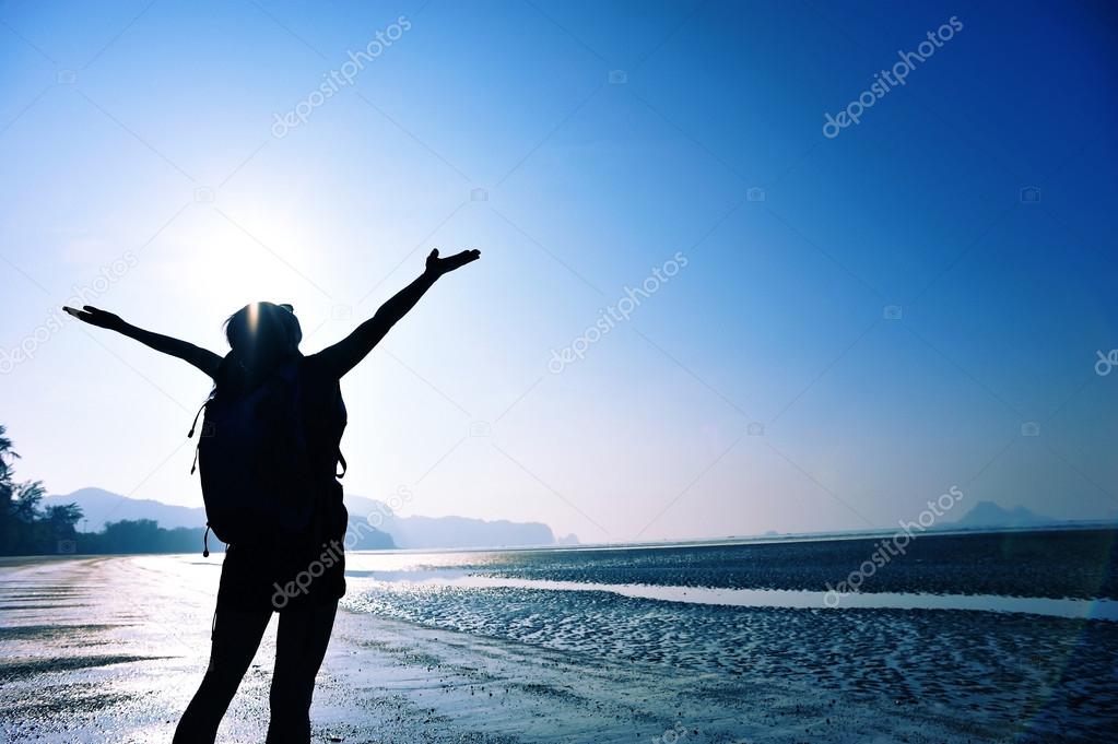 Cheering woman with open arms on beach