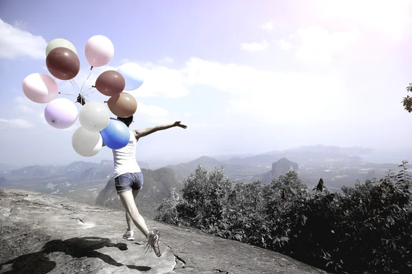 Junge Frau läuft mit bunten Luftballons — Stockfoto