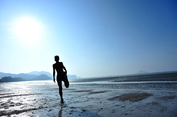 Kvinnan sträcker sig på stranden — Stockfoto