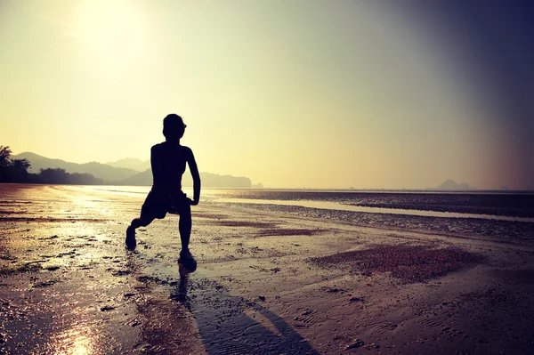 Frau dehnt sich am Strand — Stockfoto